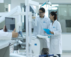 Image de deux personnes portant des blouses de laboratoire et des gants de protection en train d’inspecter un matériel médical.