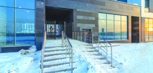 Staircase of a residential apartment complex with metal steel railing is covered with snow